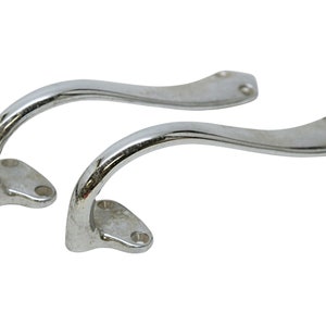 Op de afbeelding: Twee verchroomde metalen handvatten met een gebogen ontwerp. De handvatten hebben een gladde, gepolijste afwerking en zijn ontworpen om te worden gemonteerd.