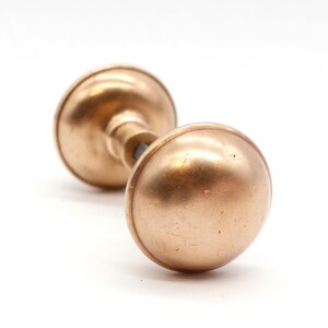 May include: A vintage brass door knob with a round shape and a smooth, polished finish.