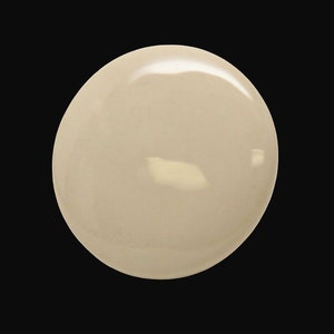 Peut inclure: Gros plan sur un objet rond, beige clair, lisse et brillant. L'objet est isolé sur un fond noir.