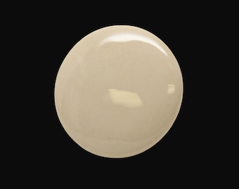 May include: A close-up of a round, light beige, smooth, and shiny object. The object is isolated on a black background.