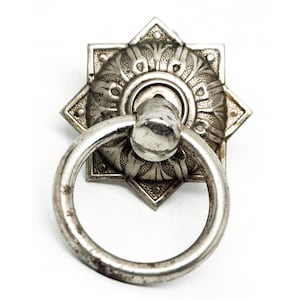 May include: Silver ring pull cabinet hardware with a star-shaped decorative backplate.