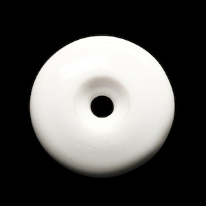Pode incluir: Botão redondo de cerâmica branca com um pequeno furo no centro.