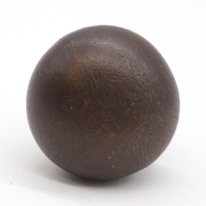 Puede incluir: Una bola redonda y lisa de color marr&oacute;n oscuro.