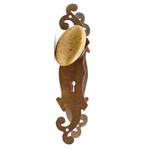 May include: An antique brass door handle with a decorative, ornate design. The handle has a keyhole and a round knob.