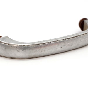 May include: A silver metal cabinet handle with a rounded shape and a slightly textured surface.