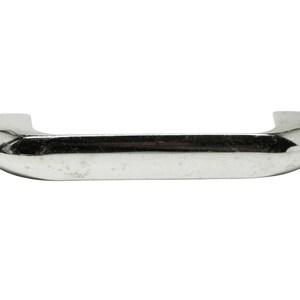 May include: A chrome-plated metal handle with rounded edges. The handle is designed for pulling open a door or drawer.