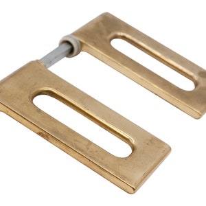 May include: A pair of gold-toned metal door hinges with a rectangular shape and a single oval-shaped cutout in each hinge.