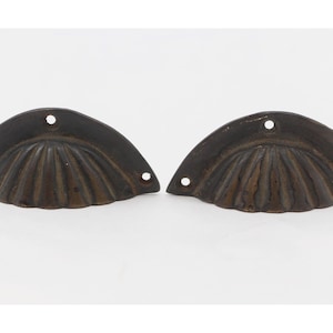 May include: Two antique bronze drawer pulls with a scalloped shell design.