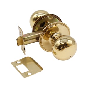 Puede incluir: Un pomo de puerta dorado con una manija redonda y un pestillo cuadrado. El pomo está diseñado para una puerta estándar.