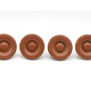 May include: Four brown wooden knobs with a raised ring around the centre. The knobs have a slightly distressed finish.