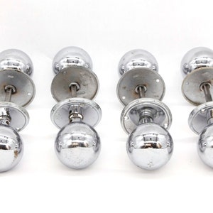May include: Four chrome door knobs with a round design. Each knob has a round base and a round top.