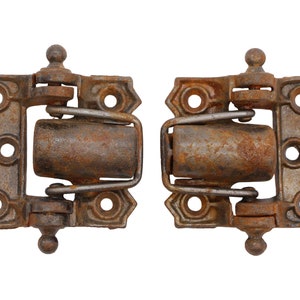 May include: Two rusty metal hinges with a rounded top and a spring mechanism. The hinges are in a closed position.