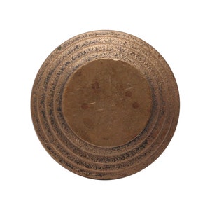 Peut inclure: Un objet rond en métal de couleur dorée avec des cercles concentriques sur le bord extérieur. Le centre de l'objet est lisse et légèrement surélevé.