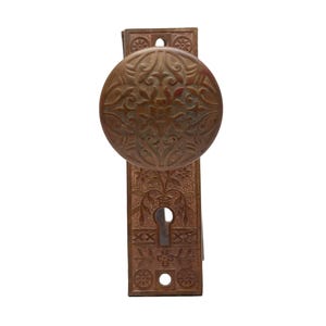 May include: A vintage brass door knob with a decorative floral design. The knob is attached to a rectangular plate with a keyhole.