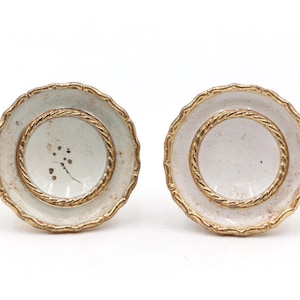 May include: Pair of white ceramic cufflinks with gold trim and a rope design. The cufflinks have a white background with a subtle pattern.