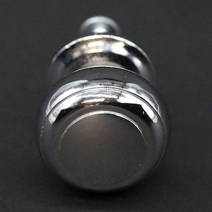 Peut inclure: Un bouton chromé de forme ronde et légèrement bombée. Le bouton a une finition lisse et brillante.
