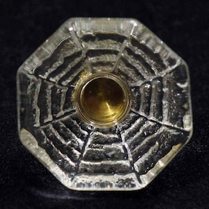 以下が含まれることがあります： 蜘蛛の巣模様のテクスチャが施された八角形の透明なガラスノブで、真鍮製のセンターが付いています。