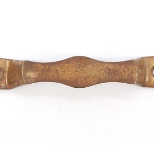 May include: A brass door handle with a curved design and two holes for mounting.