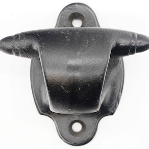 May include: Black metal wall mounted hook with a rounded, oval-shaped base and a pointed, curved hook. The hook has a smooth, matte finish.