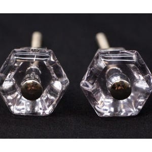 May include: Two clear glass hexagonal cabinet knobs with silver metal bases.