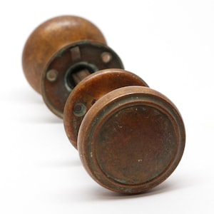 May include: A set of three antique brass door knobs with a rounded, slightly domed shape. The knobs have a worn, aged patina and are in good condition.