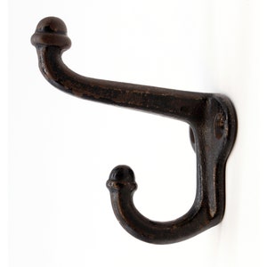 May include: A black metal double hook with rounded ends. The hook is mounted on a white wall.