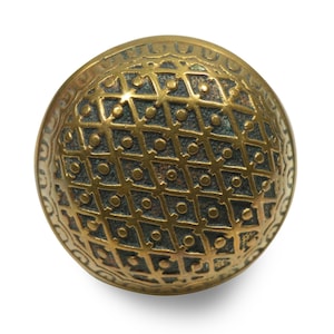 Pode incluir: Um puxador redondo de latão antigo com um padrão geométrico detalhado. O puxador tem um design de grade de diamante com pequenos detalhes circulares e uma aparência ligeiramente envelhecida. O puxador é provavelmente para um armário ou gaveta.