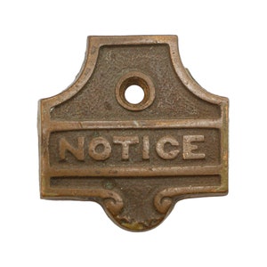 Puede incluir: Un letrero vintage de latón con la palabra "NOTICE" en relieve. El letrero tiene un agujero en la parte superior para colgarlo.