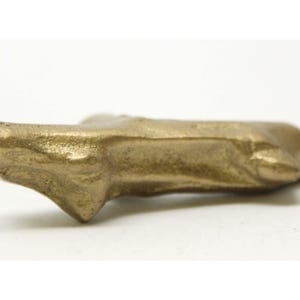 Può includere: Una piccola scultura in metallo di colore dorato, astratta e di forma organica asimmetrica.