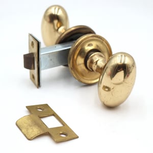 Puede incluir: Un juego de pomos para puerta en latón pulido que incluye dos pomos de forma ovalada, un mecanismo de cierre central de metal con una placa frontal rectangular y un cerradero de latón independiente con dos orificios para tornillos.