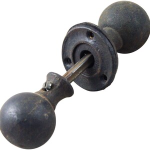 May include: A black cast iron door knob with a round handle and a round backplate.