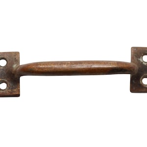 Puede incluir: Una manilla de puerta de metal marrón rústico con dos agujeros a cada lado.