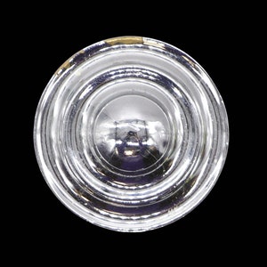 May include: A clear glass lens with a series of concentric rings. The lens is designed to focus light.