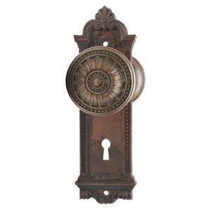 May include: A vintage-style door knob with a decorative, ornate design. The knob is made of brass and has a dark brown finish. The knob is attached to a rectangular plate with a keyhole.