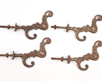 Può includere: Quattro maniglie antiche per cassetti color bronzo con disegni ornati e a spirale. Ogni maniglia presenta un ornamento decorativo con una gemma trasparente centrale e un bullone filettato per il fissaggio. Le maniglie sono disposte su sfondo bianco.