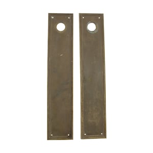 Puede incluir: Dos placas de puerta de latón antiguo con una cerradura en el centro. Las placas son rectangulares y tienen un borde decorativo.