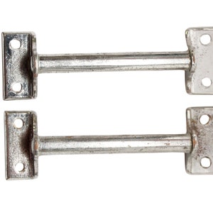 May include: Two silver metal door or window latches with a T-shaped handle and a round rod.