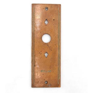 May include: A rectangular brass door plate with a round button and two diamond-shaped cutouts. The plate has a green border and the word "MILLAR" is engraved at the bottom.