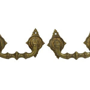 May include: A pair of antique brass drawer pulls with ornate, diamond-shaped plates and a curved,  looped handle.