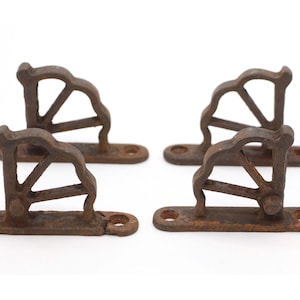 May include: Set of four rusty cast iron shelf brackets with a decorative fan design. Each bracket has two screw holes for mounting.