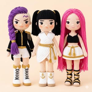 May include: Three handmade crochet dolls with detailed features. The dolls have different hairstyles, including purple braids, black pigtails, and pink flowing hair. Each doll wears unique outfits, such as a black and gold jacket, a white wrap dress, and a black crop top with a white skirt.