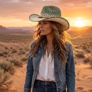 May include: A crochet hat featuring a sage green crown with an open-weave pattern, a cream-colored band, and a wide brim with a sage green edge. The hat is accented with a thin brown cord and small wooden beads around the base of the crown.
