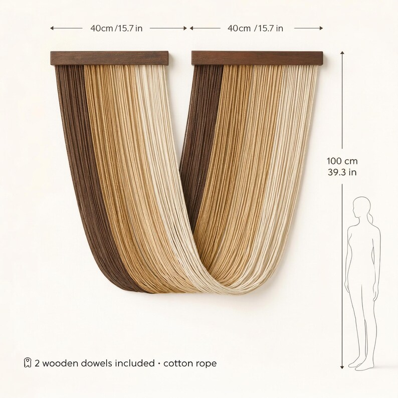 May include: A wall hanging with a modern design. It features two wooden dowels, each 15.7 inches long, supporting strands of cotton rope in shades of brown, beige, and cream. The hanging is 39.3 inches tall. The text says "2 wooden dowels included &bull; cotton rope."
