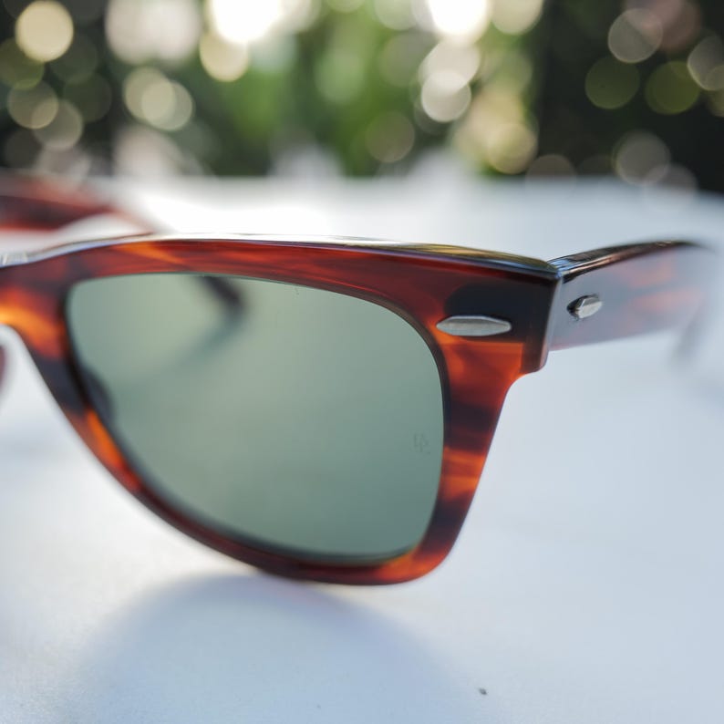 May include: Tortoiseshell-patterned sunglasses with a brown and black marbled frame and dark green lenses. The frame features silver-toned metal accents at the hinges and temples, providing a classic look with a smooth, polished finish throughout.