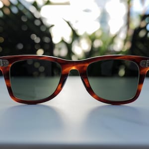 May include: Tortoiseshell-patterned sunglasses with a classic rectangular frame shape. The frames feature a brown and amber marbled design with silver-toned metal accents at the hinges. The lenses are dark green and provide full coverage.