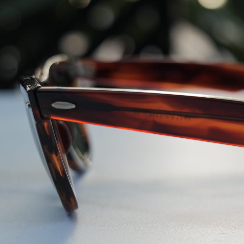 May include: Tortoiseshell-patterned eyeglasses featuring a brown and amber marbled frame with a glossy finish. The side temple arm displays a small silver-toned metal accent near the hinge, showcasing a classic rectangular shape and smooth texture.