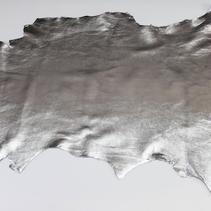 Peut inclure: Une grande pièce de cuir argenté de forme irrégulière. Le cuir a un aspect métallique et une surface texturée. Les bords sont inégaux, ce qui lui donne un aspect naturel. Le matériau est probablement utilisé pour des projets de création ou de design.