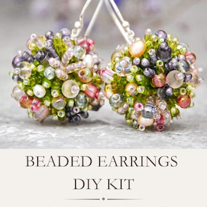 Puede incluir: Un par de pendientes esféricos de cuentas con una mezcla de cuentas de vidrio verdes, rosas, moradas y transparentes con ganchos plateados. El texto debajo dice: BEADED EARRINGS DIY KIT. Materials + Tutorial.