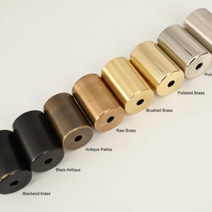 Puede incluir: Una variedad de herrajes met&aacute;licos cil&iacute;ndricos en varios acabados, desde negro hasta lat&oacute;n. La imagen muestra opciones etiquetadas como "Blackend brass", "Black Antique", "Antique Patina", "Raw Brass", "Brushed Brass", "Polished Brass", "Polished Chrome" y "Brushed chrome".
