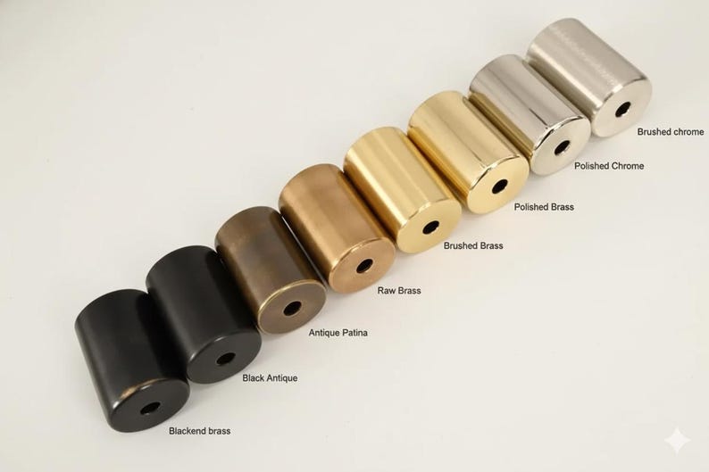 Puede incluir: Una variedad de herrajes met&aacute;licos cil&iacute;ndricos en varios acabados, desde negro hasta lat&oacute;n. La imagen muestra opciones etiquetadas como "Blackend brass", "Black Antique", "Antique Patina", "Raw Brass", "Brushed Brass", "Polished Brass", "Polished Chrome" y "Brushed chrome".